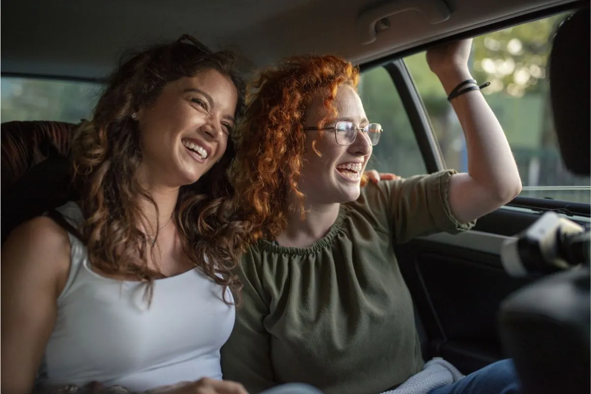 Happy women couple traveling by car